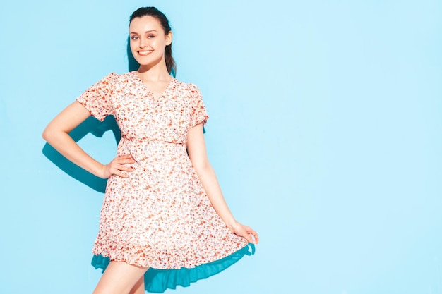 Portrait of young beautiful smiling female in trendy summer blue dress Sexy carefree woman posing near blue wall in studio Positive model having fun and going crazy Cheerful and happy