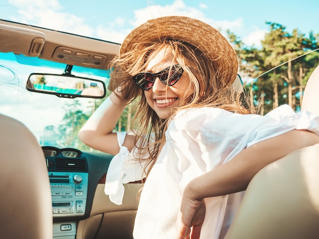 Portrait of young beautiful and smiling hipster girl in convertible car