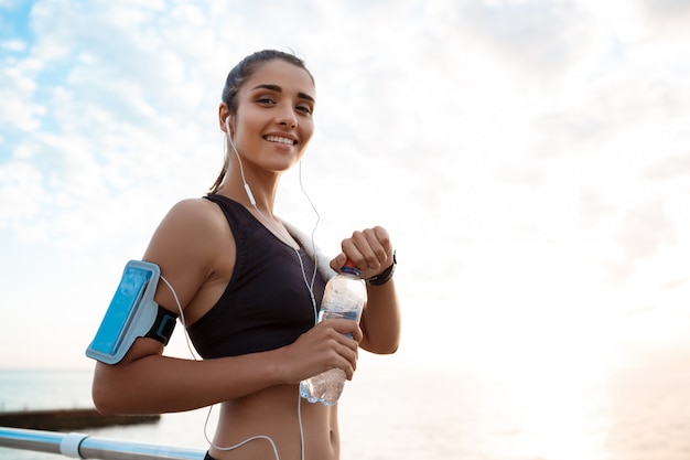 Portrait of young beautiful sportive girl at sunrise over seaside.