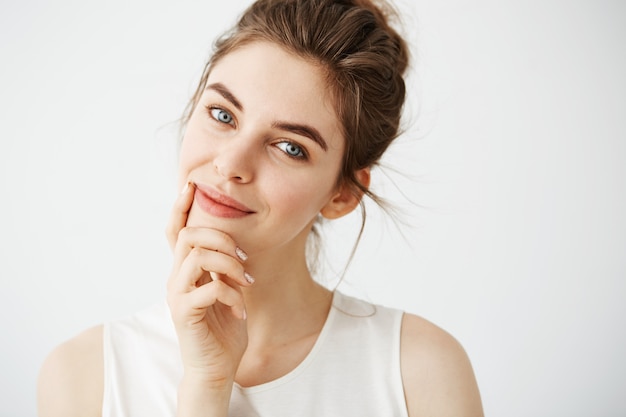 Portrait of young beautiful tender woman with bun smiling touching face