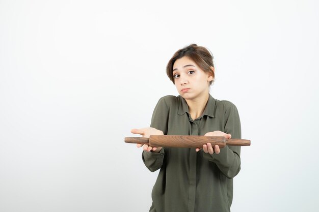 Portrait of young beautiful woman holding wooden rolling pin. High quality photo