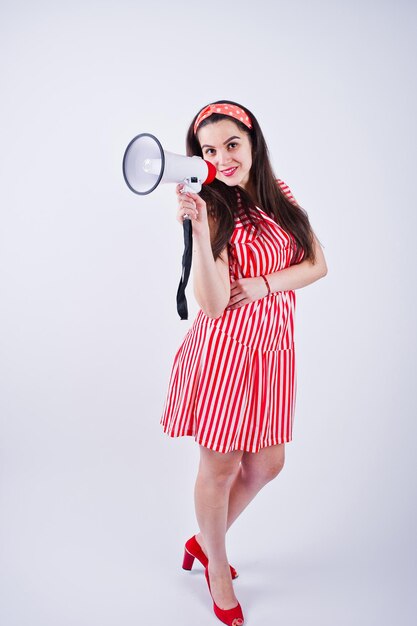 Portrait of a young beautiful woman in red dress talking into megaphone