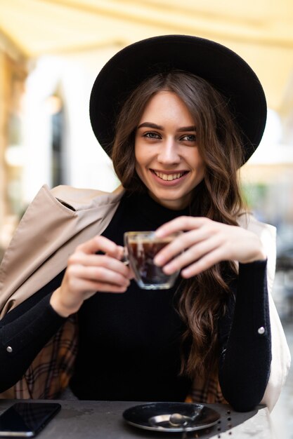 Portrait of young beautiful woman sitting in a cafe outdoor drinking coffee