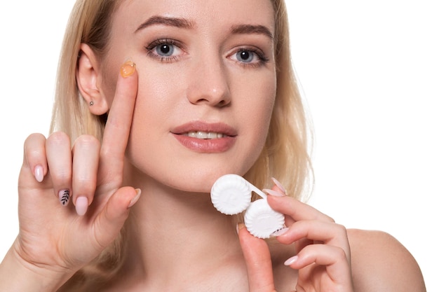 Portrait of young beautiful woman with natural makeup and contact eye lens in hand. Close-up of female model holding white lens box. Eye care and healthy lifestyle. Eyes health.