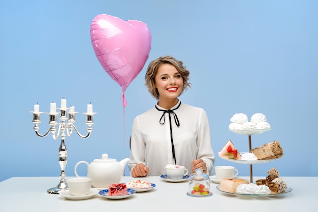 Free photo portrait of young beautiful woman with sweets over blue wall