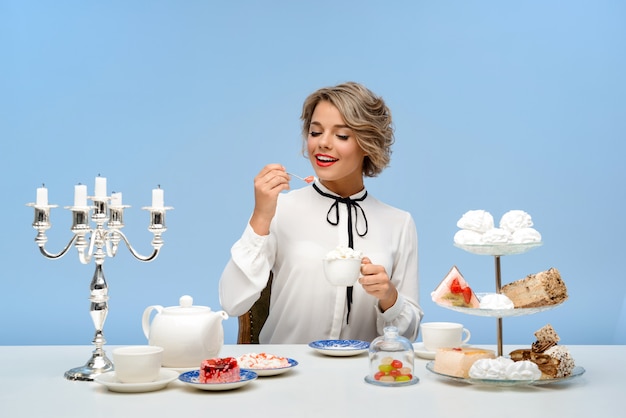 Free Photo portrait of young beautiful woman with sweets over blue wall