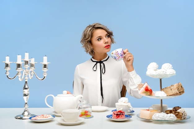 Free photo portrait of young beautiful woman with sweets over blue wall