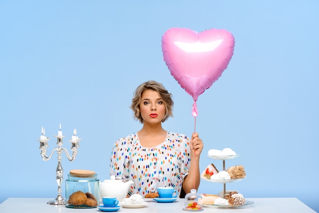 Free photo portrait of young beautiful woman with sweets over blue wall