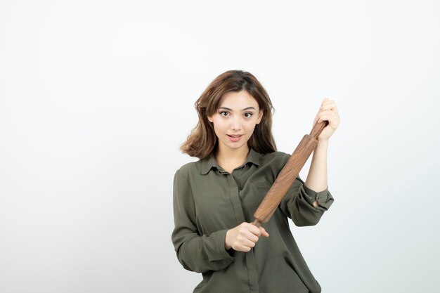 Portrait of young beautiful woman with wooden rolling pin standing. High quality photo