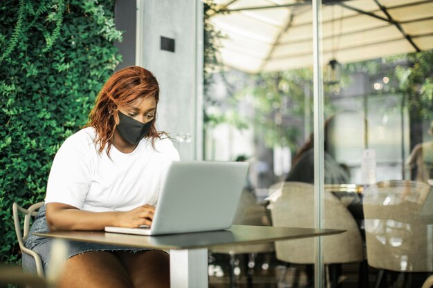 portrait of young black woman using a computer with mask