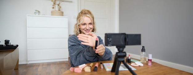 Portrait of young blond woman teenage girl records video for her social media account shows makeup