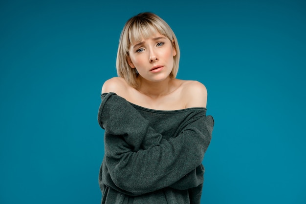 Portrait of young blonde pretty woman over blue wall