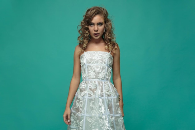 Free Photo portrait of young blonde in white dress on blue background