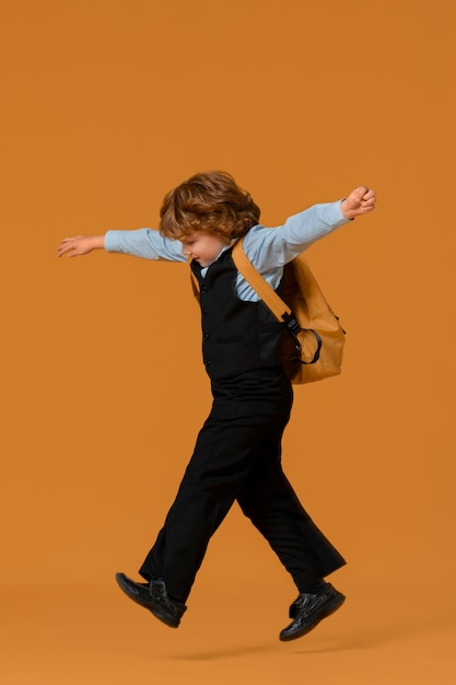 Free Photo portrait of young boy student in school uniform jumping mid-air