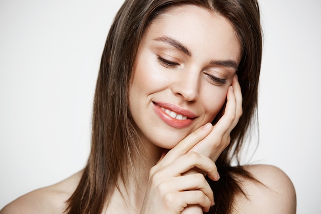 Portrait of young brunette beautiful woman smiling touching face. Spa beauty healthy and cosmetology concept.