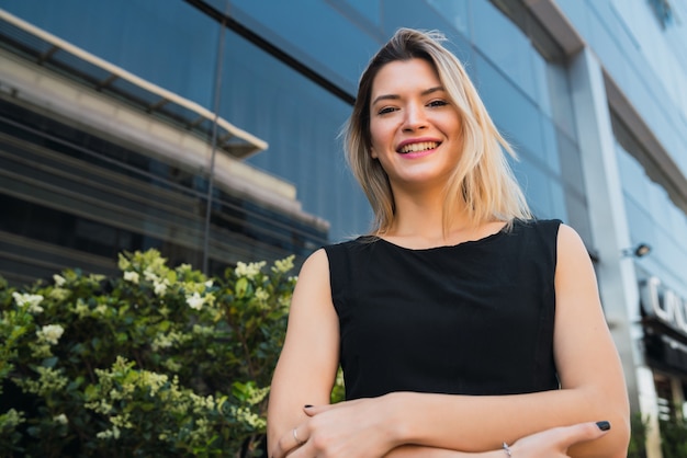 Portrait of young business woman standing outside office buildings. Business and success concept.