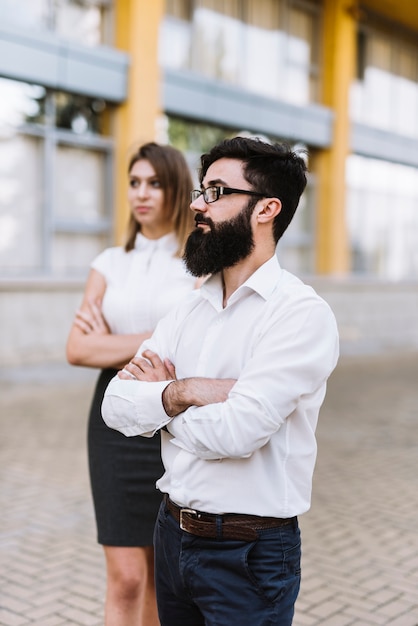 Portrait of young businessman and businesswoman standing with arm crossed