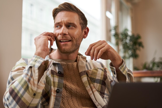 Free Photo portrait of young businessman freelancer working remotely from coffee shop in city sitting in chair