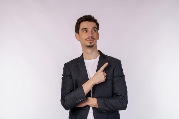 Portrait of young businessman pointing fingers at copy space isolated on white studio background