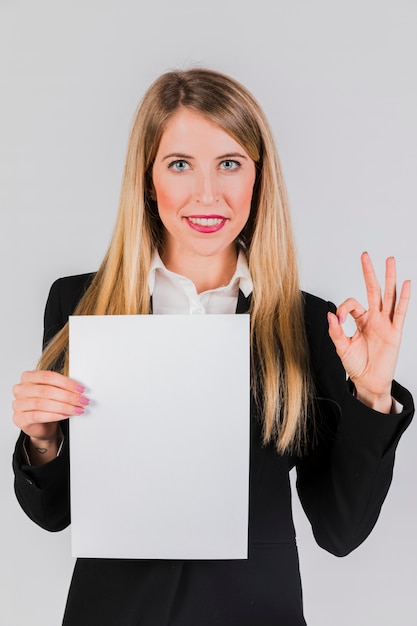 Free photo portrait of a young businesswoman holding the white paper in hand showing ok sign