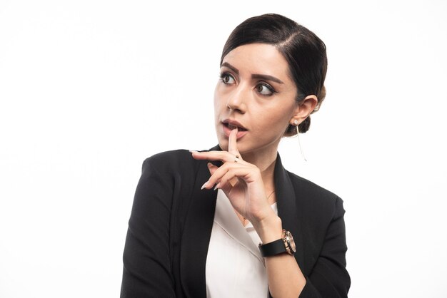 Portrait of young businesswoman posing on white wall.