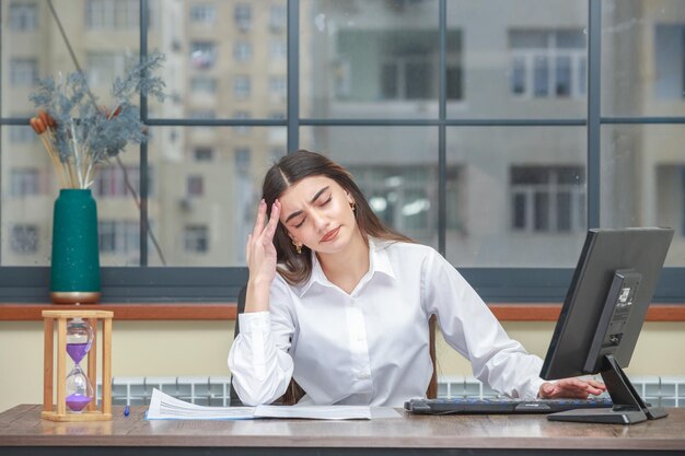 Portrait of a young businesswoman sitting at the desk and feeling tired High quality photo