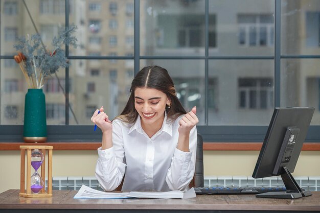 Portrait of a young businesswoman sitting at the desk and squeeze her fists High quality photo