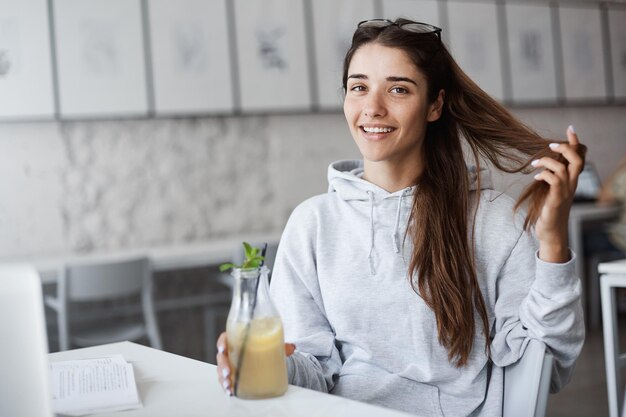 Free photo portrait of young careless woman drinking lemonade caring less about her studies planning on going shopping on holidays