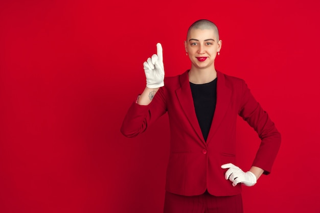 Portrait of young caucasian bald woman on red wall