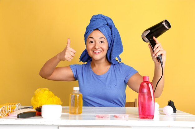 Portrait of young caucasian woman in her beauty day, skin and hair care routine. Female model with natural cosmetics applying cream and oils for make up. Body and face care, natural beauty concept.