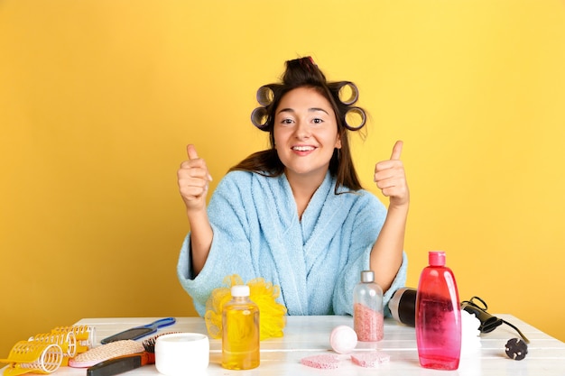 Portrait of young caucasian woman in her beauty day, skin and hair care routine. Female model with natural cosmetics applying cream and oils for make up. Body and face care, natural beauty concept.