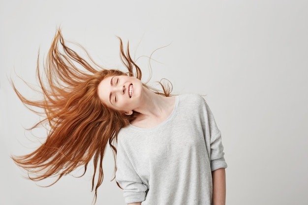 Free photo portrait of young cheerful beautiful redhead girl smiling with closed eyes shaking head and hair .