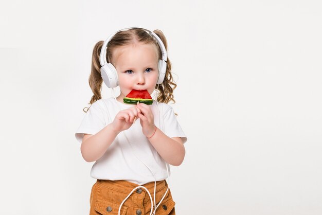 Portrait of young child girl in headset eat candy