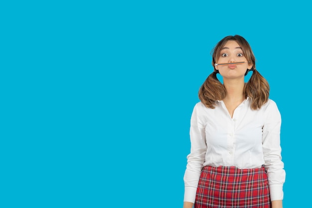 Portrait of young college girl making mustache with pen. High quality photo