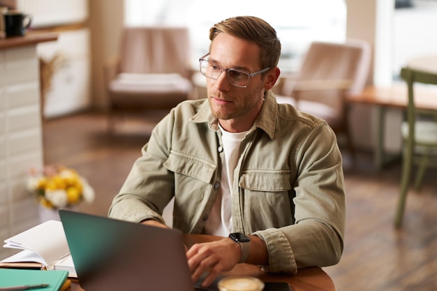 Free Photo portrait of young concentrated man in glasses working from coffee shop studying looking thoughtful