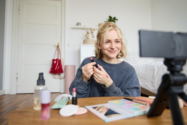 Free photo portrait of young content maker woman blogger recording a video on digital camera showing lipstick