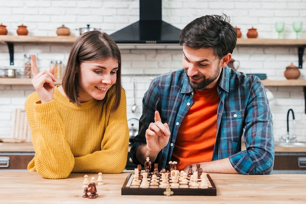 Portrait of a young couple playing the chess in the kitchen