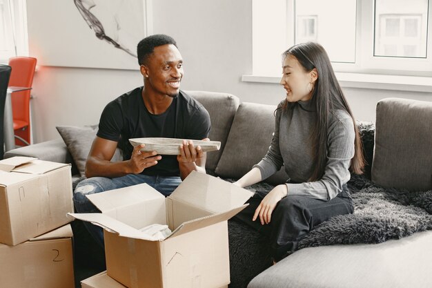 Portrait of young couple with cardboard boxes at new home, moving house concept.