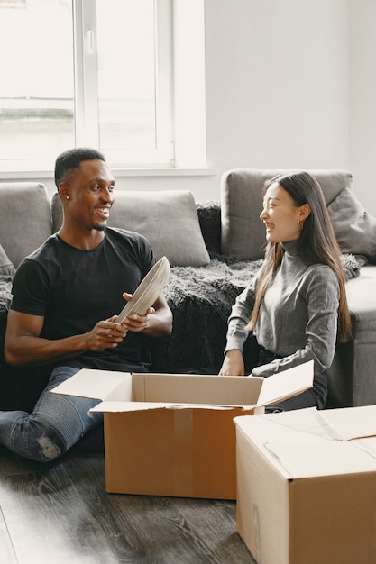 Portrait of young couple with cardboard boxes at new home, moving house concept.