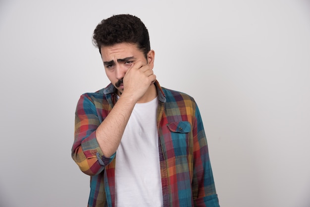 Portrait of young crying man trying to stop his tears.