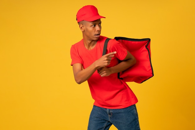 Portrait of young delivery man dressed in a red uniform running over isolated background. Delivery concept.