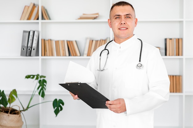 Free Photo portrait of young doctor holding a clipboard