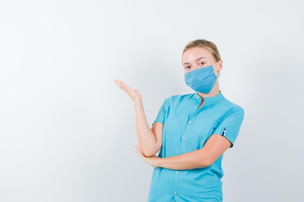 Portrait of young female doctor holding something in uniform isolated