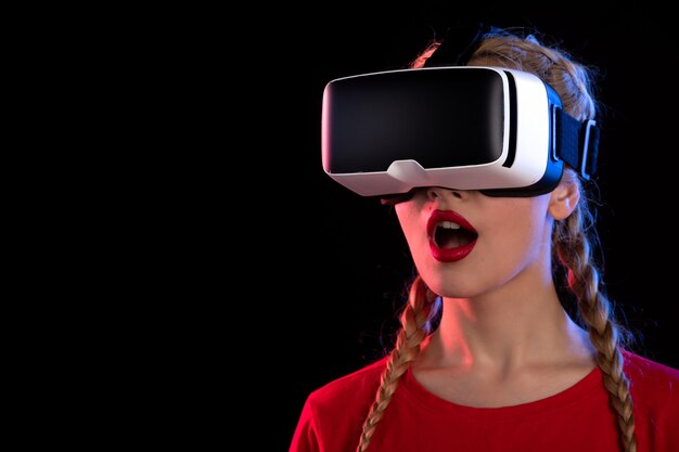 Portrait of young female excitedly playing virtual reality on dark wall