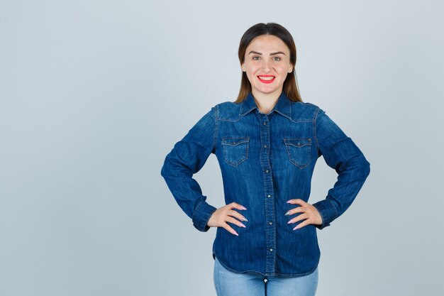 Free Photo portrait of young female keeping hands on hip in denim shirt and jeans and looking gorgeous front view