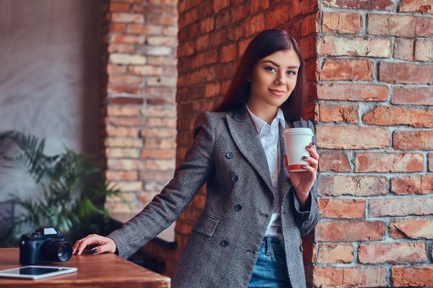 Portrait of a young female photographer holds a cup of a morning