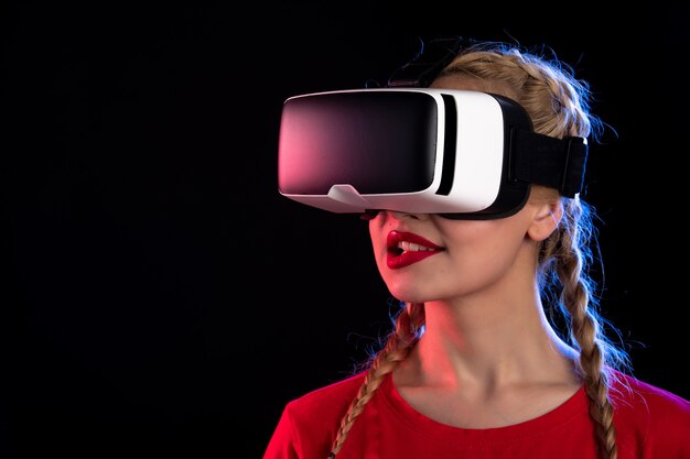 Portrait of young female playing virtual reality on dark wall