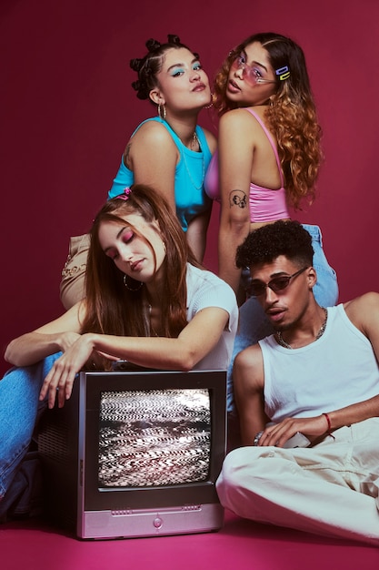 Free Photo portrait of young friends in 2000s fashion style posing with television