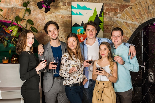 Free photo portrait of young friends holding glasses of drinks at nightclub