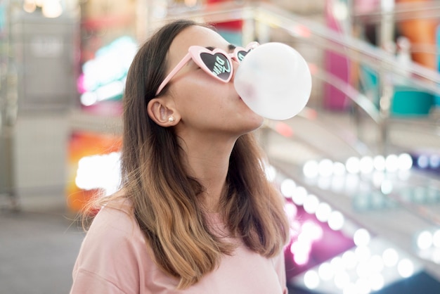 Free photo portrait of young girl blowing bubble gum